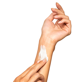 a hand applying cream to their forearm